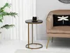 A small round side table with a black marble top and gold legs, placed next to a beige armchair with a black cushion featuring a dragonfly design. A plant is visible on the left. Anteprima dell’immagine prodotto