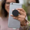 A person is holding a smartphone with a PopSocket attached. Produktbild-Vorschau