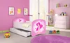 A child's bedroom with a pink theme, featuring a bed, dresser, and toys. Náhled obrázku produktu