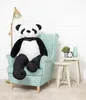 A large plush panda sits in a light blue armchair next to a small side table with a plant and clock. Voir les images du produit