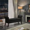 A living room scene at night with a view of a city and castle through a large window. A black storage bench is in the foreground, with a fireplace and lamp in the background. Podgląd zdjęcia produktu