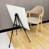 An easel with a white board is set up next to a chair. Podgląd zdjęcia produktu