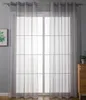 A sheer gray curtain hangs in front of a large window with a grid pattern. Produktbild-Vorschau