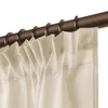 A close-up view of cream-colored curtains hanging from a bronze curtain rod with rings. Produktbild-Vorschau