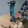 A person is using a cordless multitool to cut a piece of wood on a workbench. Náhľad obrázku produktu