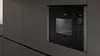 A built-in black microwave oven with a digital display and control panel, integrated into dark gray kitchen cabinetry. Náhľad obrázku produktu