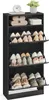A black shoe cabinet with multiple shelves and flip-down doors, filled with various shoes. A small clock and a potted plant are on top. Produktbild-Vorschau