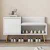 A white shoe cabinet with a bench and storage compartment, featuring gold legs and a padded seat with a backrest. Several pairs of shoes are displayed on the shelves and on the floor in front of the cabinet. Anteprima dell’immagine prodotto
