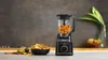 A Ninja blender filled with chopped vegetables sits on a kitchen counter next to a bowl of tortilla chips and limes. Produktbild-Vorschau