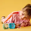 A young girl is playing with Lego Friends cubes on a yellow background. Anteprima dell’immagine prodotto