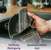 A hand is rinsing a dark gray kitchen gadget under a running faucet in a sink. The gadget has a perforated design. Text overlays indicate features like 'Easy Cleaning' and 'Dishwasher Safe'. Produktbild-Vorschau