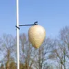 A decorative wasp nest-shaped lantern hanging from a pole against a clear blue sky with bare trees in the background. Produktbild-Vorschau