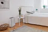 A bedroom scene with an air purifier next to a bed. Podgląd zdjęcia produktu