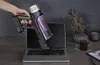 A hand holding a vacuum cleaner emerging from a laptop screen, on a desk with other items. Voir les images du produit