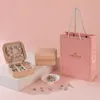 A jewelry-making kit with a pink gift bag, a jewelry box, and various charms and beads. Produktbild-Vorschau