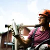 A person wearing a hard hat and gloves holds a silver water bottle. Náhled obrázku produktu