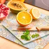 A close-up shot of various fruits, including a halved orange, papaya, and pomegranate, arranged on decorative cutting boards with mint leaves and a knife. Náhľad obrázku produktu