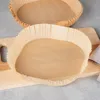 Two paper liners for an air fryer are shown on a wooden cutting board. Podgląd zdjęcia produktu