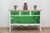 A dresser with a decorative film on the drawers, placed against a white wall with a wooden floor. Produktbild-Vorschau