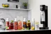 A collection of drinks and a soda maker on a kitchen counter. Produktbild-Vorschau