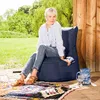 A woman is sitting on a beanbag chair on a patio. Produktbild-Vorschau