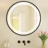 A round LED bathroom mirror with a black metal frame is shown above a sink with faucets and soap dispensers. Pink tulips in a vase are to the right. Produktbild-Vorschau