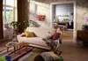 A cozy living room with a sofa, coffee tables, and a view into a kitchen. Produktbild-Vorschau