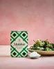 A box of Maldon Sea Salt Flakes is placed next to a bowl of green peppers sprinkled with salt, and a small spoon with salt. Podgląd zdjęcia produktu