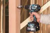 A person is using a cordless drill to make a hole in a wooden beam. Produktbild-Vorschau