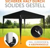 A black pop-up tent is set up in a grassy outdoor area, with text overlays highlighting its features and included accessories. Produktbild-Vorschau