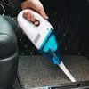 A hand holding a white and blue handheld vacuum cleaner inside a car. Náhled obrázku produktu