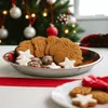 A close-up of a metal plate filled with Christmas cookies and star-shaped cookies, with a decorated Christmas tree in the background. Produktbild-Vorschau