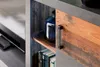 A close-up view of a wooden and gray storage unit with a blue vase and books on a shelf. Produktbild-Vorschau