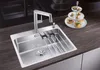 A stainless steel kitchen sink with a modern faucet and a tiered stand of appetizers in the background. Náhled obrázku produktu