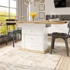 A dining table with a pull-out extension and storage drawers, set in a bright, modern dining room with large windows and a rug.