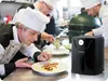 Chefs in a kitchen preparing food, with an air fryer in the foreground. Anteprima dell’immagine prodotto
