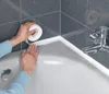 A person is applying white sealing tape to the edge of a bathtub. Náhled obrázku produktu