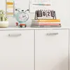 A white cabinet with decorative items on top, including a cactus, a clock, and books. Podgląd zdjęcia produktu