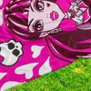 A close-up of a Monster High blanket with a character's face and hearts, lying on grass. Produktbild-Vorschau