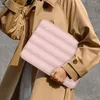 A person wearing a trench coat holds a pink laptop bag. Náhľad obrázku produktu