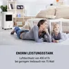A woman and a child lying on the floor in a living room, with a portable air cooler in the background. Produktbild-Vorschau