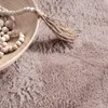 A close-up view of a fluffy pink rug with a wooden bowl filled with wooden beads and a jute tassel. Produktbild-Vorschau