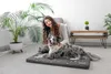 A woman is petting her dog on a dog bed in a living room. Náhľad obrázku produktu