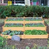 A tiered wooden raised garden bed filled with various plants, set outdoors in a garden environment. Produktbild-Vorschau