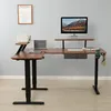 An L-shaped standing desk with a computer, monitor stand, printer, and speaker. Produktbild-Vorschau
