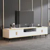 A modern white TV stand with gold accents and black legs, featuring a large flat-screen TV on top. Podgląd zdjęcia produktu