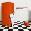 A man in a white suit stands next to an orange structure on a black and white checkered floor. Text is visible on the wall. Produktbild-Vorschau