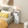 A white narrow cabinet with drawers next to a bed in a bedroom. Produktbild-Vorschau