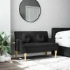 A black sofa with two round cushions is placed in a room next to a bed and a large plant. Podgląd zdjęcia produktu