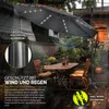 An outdoor patio scene with a large umbrella, table, and chairs, set during a rain shower. Anteprima dell’immagine prodotto